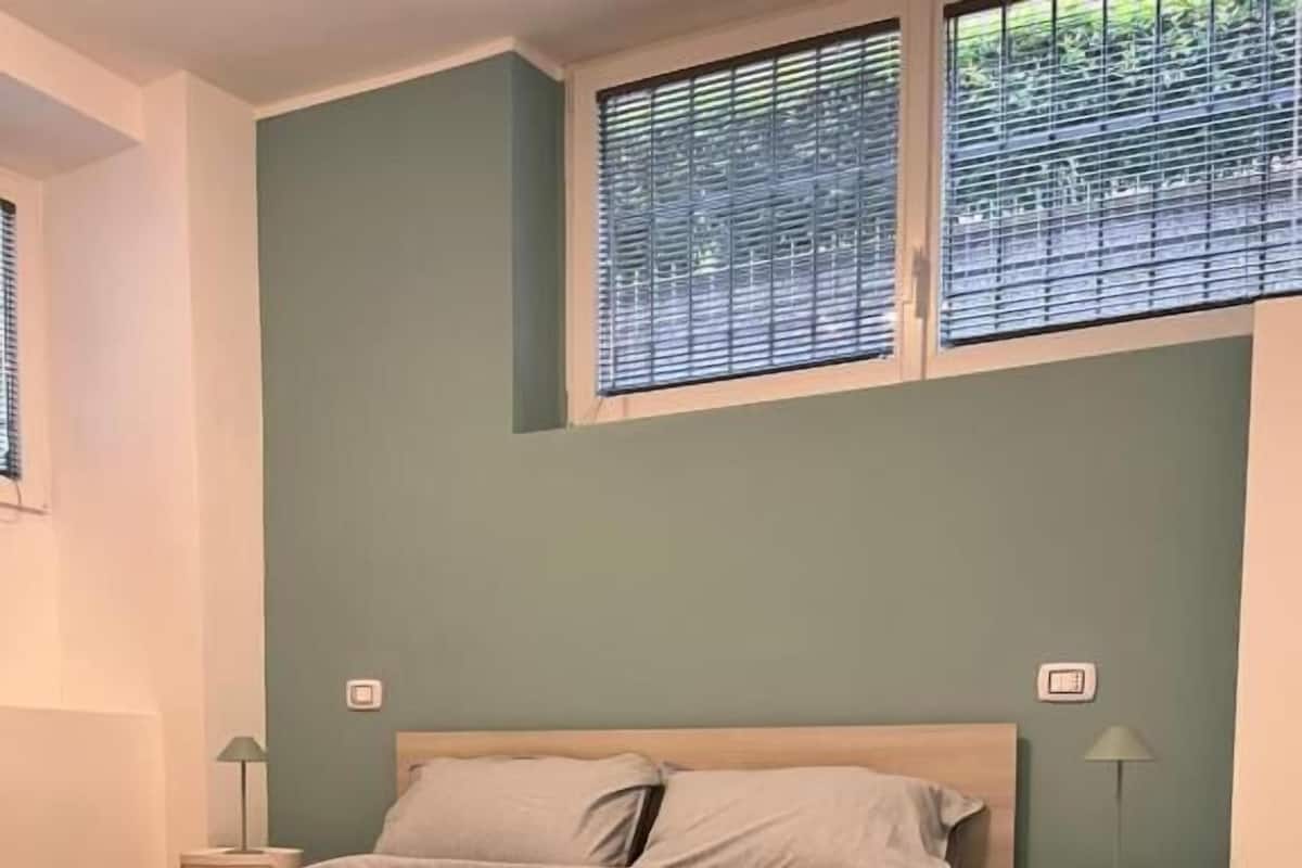 Une chambre à coucher avec un lit, des tables de chevet et une fenêtre avec des stores.