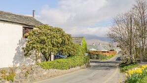 A narrow road flanked by stone walls and houses with ivy-covered walls and traditional architecture. - Farmhouse Cottage (Keswick)