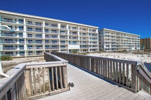 Ein mehrstöckiges Hotel mit Balkonen, einem hölzernen Steg und Blick auf den Strand.