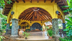 A covered outdoor area with a tiled floor, stone pillars, and a wooden ceiling. - Casa Ceiba: Lush 3BR Escape Near the Ocean (Paraíso)