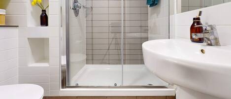 A bathroom with a glass-enclosed shower, a white sink, and a toilet.