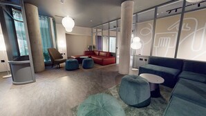 Eine moderne Lobby mit einem roten Sofa, blauen Hocker und einem grauen Boden.