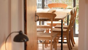 A dining area with a wooden table and chairs, a hanging pendant light, and a view of the outdoors through a large window. - Cosy and stylish, dog and family friendly cottage just south of Aviemore (Dalraddy)