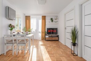 A modern living room with a dining area, a flat-screen TV, and a potted plant. - Lumina apart with balcony in Warsaw (Warsaw)