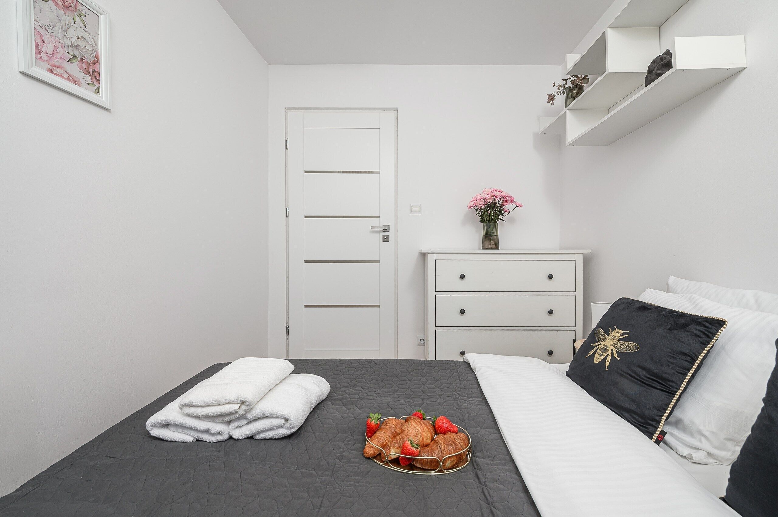 Une chambre à coucher bien rangée, avec un lit, une table de chevet et une commode, ainsi qu’une porte.