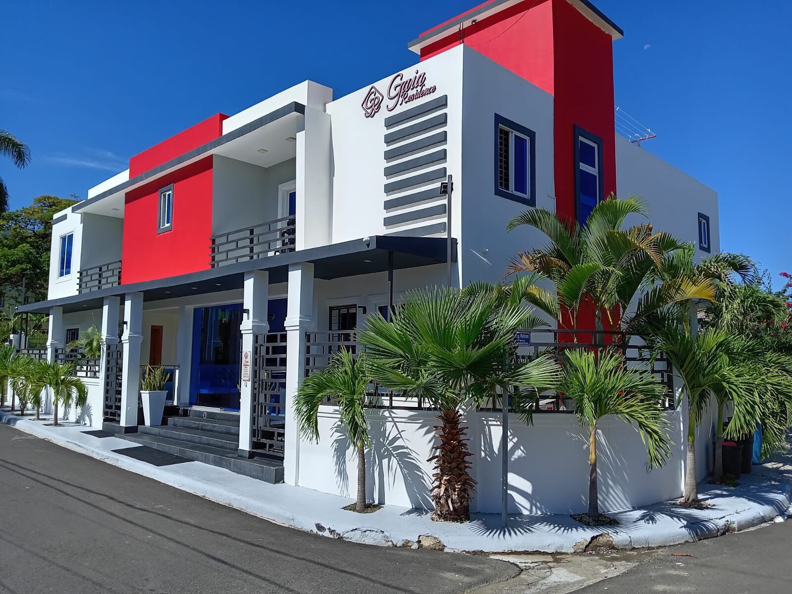 A modern two-story building with a red and white facade, featuring a prominent logo on the upper right side.