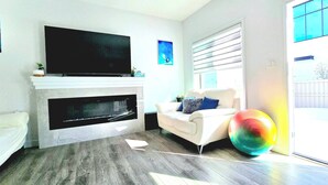 A living room with a flat-screen TV, fireplace, sofa, and a colorful exercise ball. - Modern 3BR Home Edmonton Near by Airport (Edmonton)