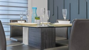 A modern dining area with a glass table, dark chairs, and a blue vase. - Modern 3BR Home Edmonton Near by Airport (Edmonton)