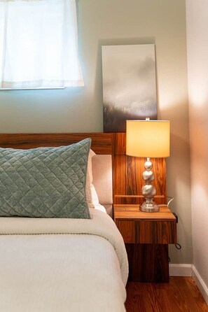A neatly made bed with a quilted pillow, a bedside table with a lamp, and a painting on the wall. - ‘Cedar’ Riverfront Cabin near Olympic National Park (Beaver)
