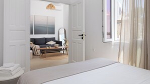 Ein modernes Schlafzimmer mit Bett, Sofa, Couchtisch und einem großen Fenster mit Vorhängen.