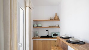 Eine kleine Küche mit Holzausstattung, einem Spülbecken, einer Kaffeemaschine, einem alten Radio und einer Essecke mit einer Bank.