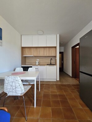 A modern kitchen with white cabinets, a built-in oven, and a stainless steel refrigerator. - Vacation apartment with garden and barbecue facilities - Apartment 2 (Valbandon)
