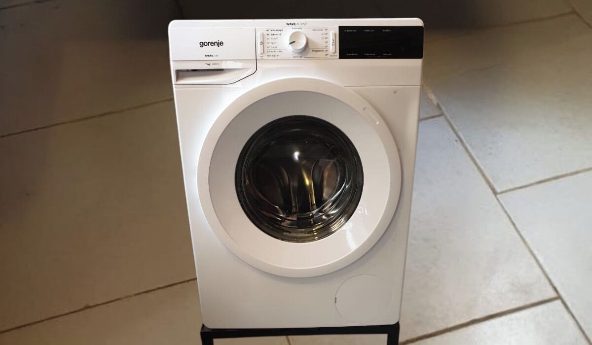 A white washing machine with a control panel, placed on a tiled floor.