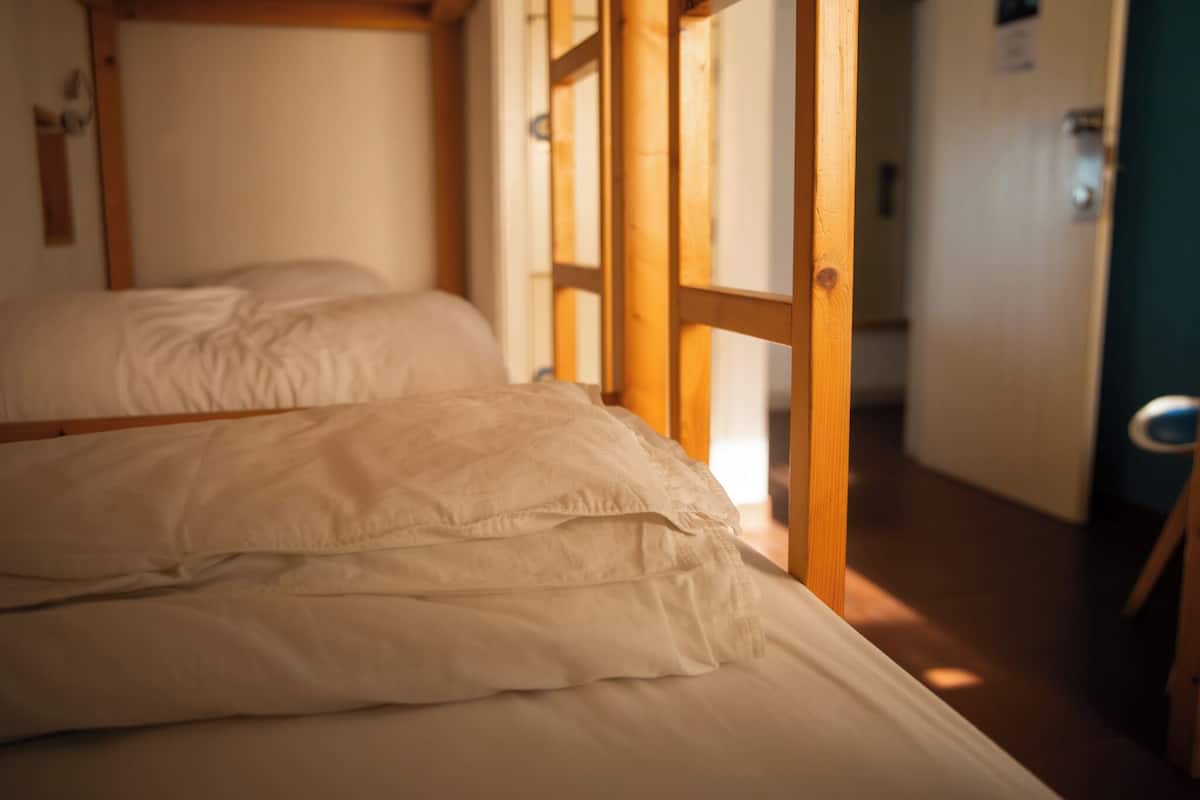 A room with two beds, wooden headboards, and a wooden door.