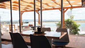 An outdoor dining area with a view of the water and dock. - Wax Hostel & Apts (Faro)