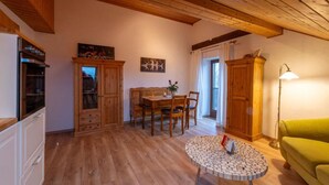 Un accogliente soggiorno con pavimento in legno, un tavolo da pranzo e un divano verde.