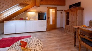 Una cucina con mobili bianchi, soffitto in legno e tappeto rosso.