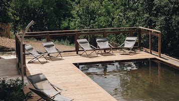 A wooden deck with lounge chairs and a swimming pool.