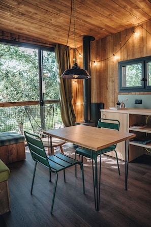 A wooden interior with a dining table, chairs, and a kitchen area.