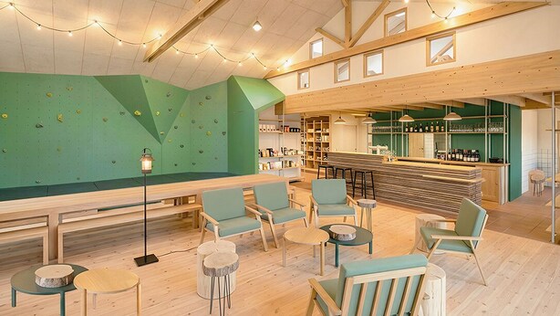 A climbing wall, seating area, bar, and shelves with bottles. - Bon Air club Alpes Mancelles (Saint-Léonard-des-Bois)