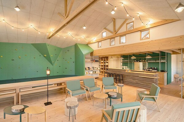 A climbing wall, seating area, bar, and shelves with bottles. - Bon Air club Alpes Mancelles (Saint-Léonard-des-Bois)