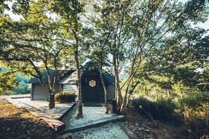 A rustic cabin with a wooden door, surrounded by trees and a gravel path. - Bon Air club Alpes Mancelles (Saint-Léonard-des-Bois)