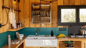 A compact kitchen with a sink, stove, and hanging light fixture. - Bon Air club Alpes Mancelles (Saint-Léonard-des-Bois)