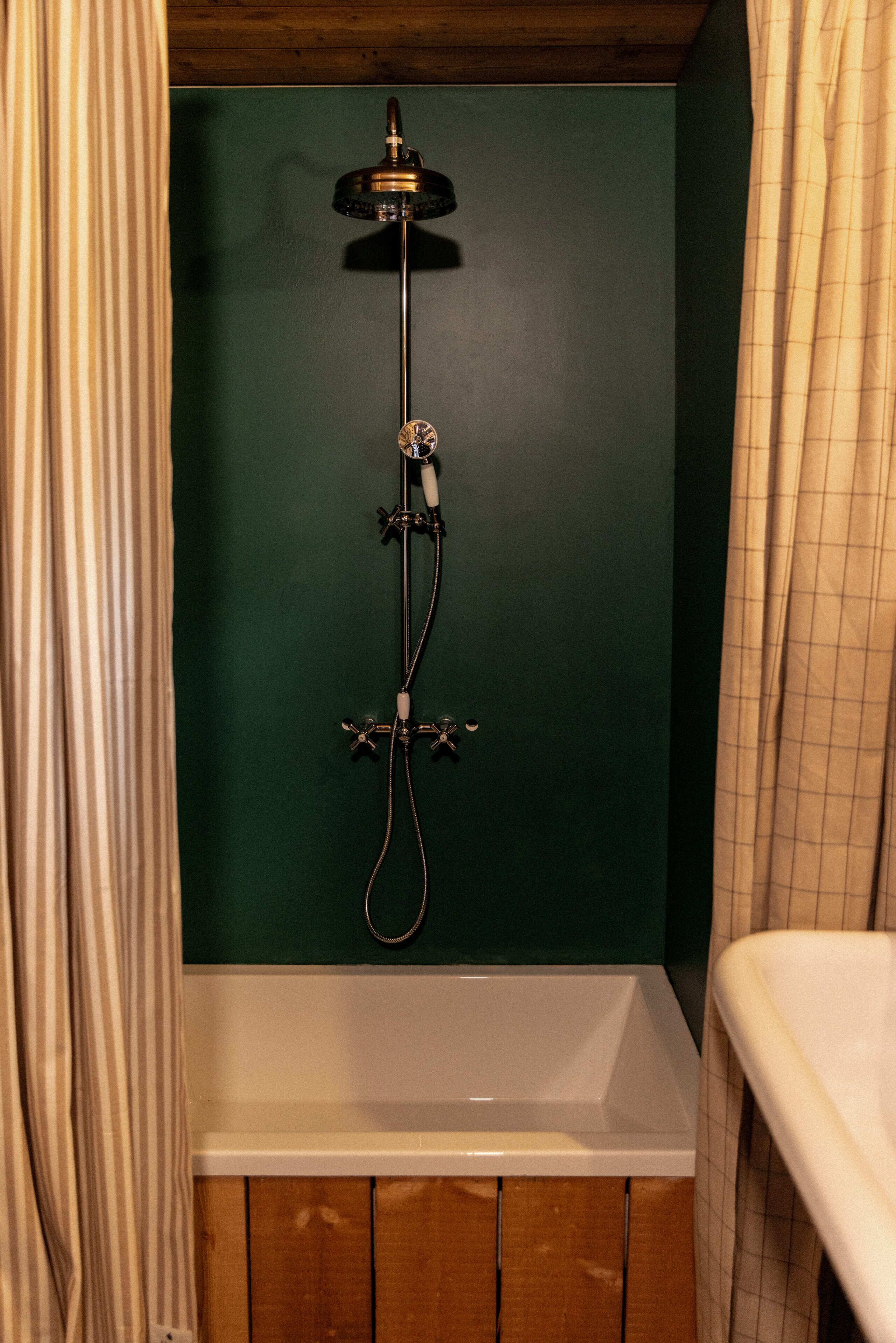 Ducha con cabezal de ducha de mano, grifo empotrado en la pared y bañera.