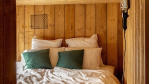 A wooden cabin-style bedroom with a bed, pillows, and a hanging light fixture. - Bon Air club Alpes Mancelles (Saint-Léonard-des-Bois)