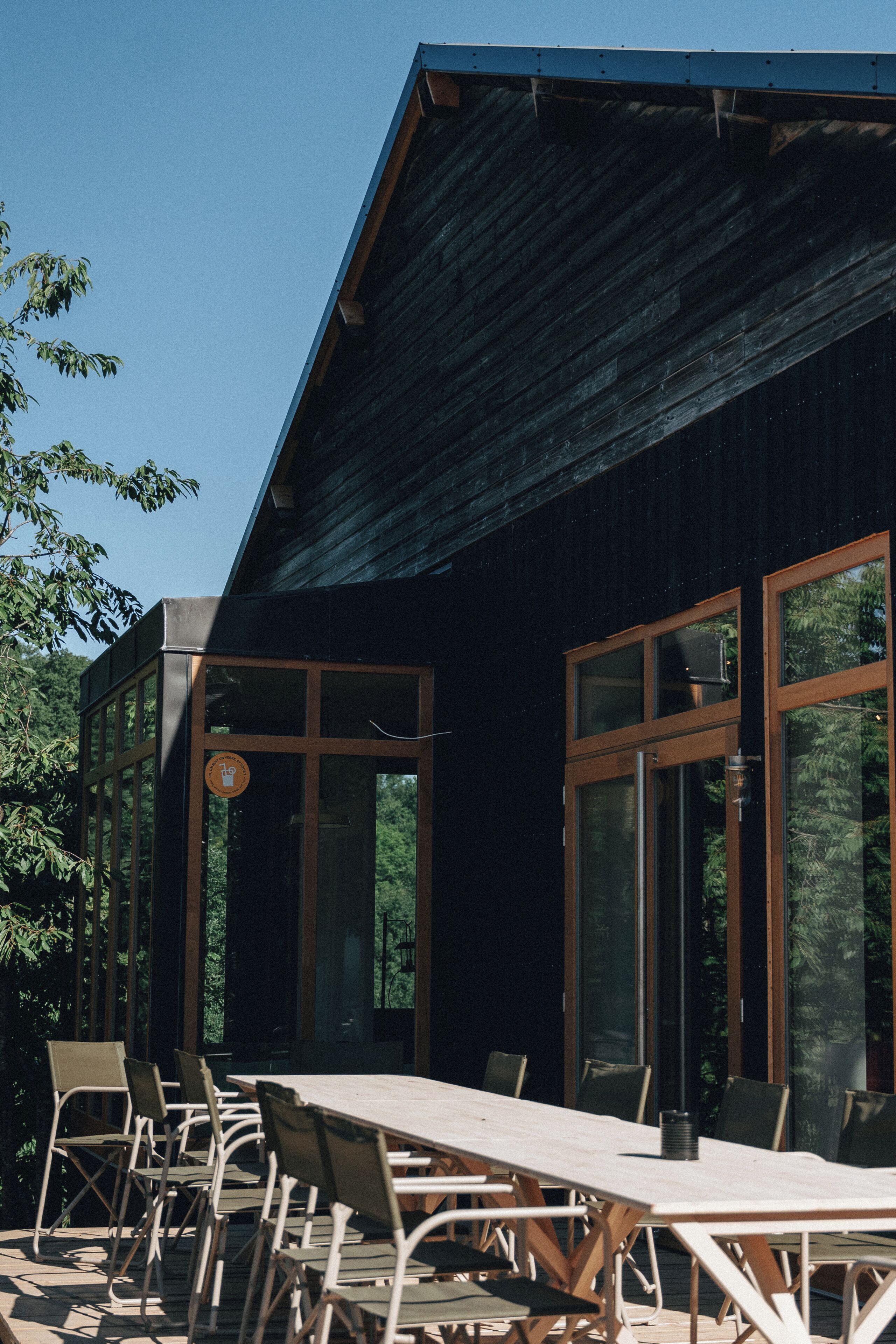 A building with a large dining area, multiple windows, and a wooden exterior.