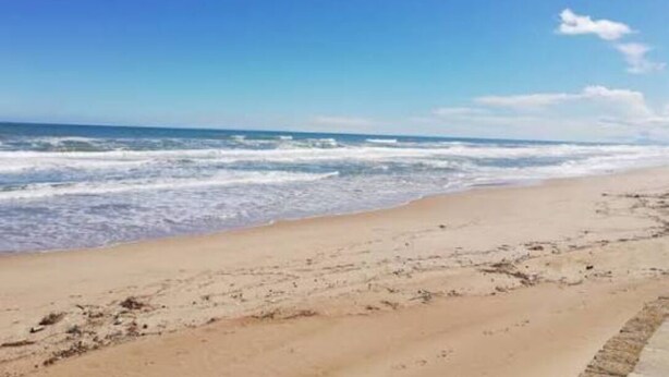 Una playa con arena y olas.