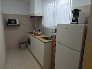 A compact kitchen with a microwave, stove, sink, and a refrigerator. - SeaSuites Yellow - Loft cerca del mar (Cullera)