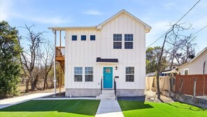 A two-story house with a front porch, a blue door, and a well-maintained lawn. - Unit 101 Family-friendly stay San Antonio 2BR for 6 (San Antonio)