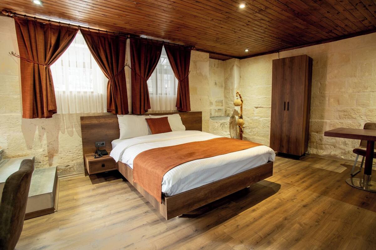 Ein Schlafzimmer mit einem hölzernen Bett, einem Nachttisch, einem Kleiderschrank und einem Esstisch.
