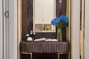 A vanity area with a mirror, a vase of flowers, and a book on a table. - Romeo Hotel Ngoai Giao Doan (Hanoi)