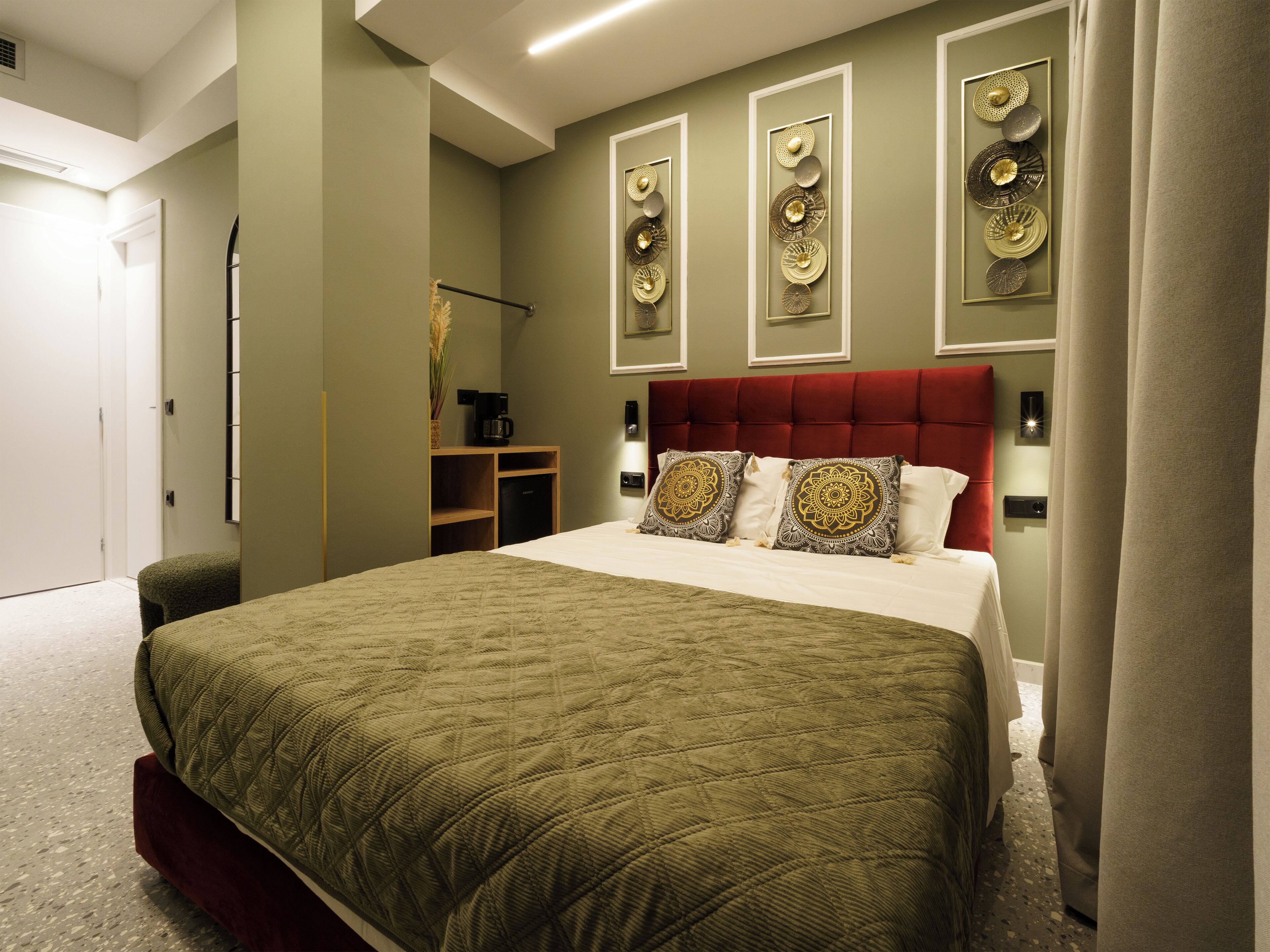 A bedroom with a large bed, a red headboard, and decorative wall art.