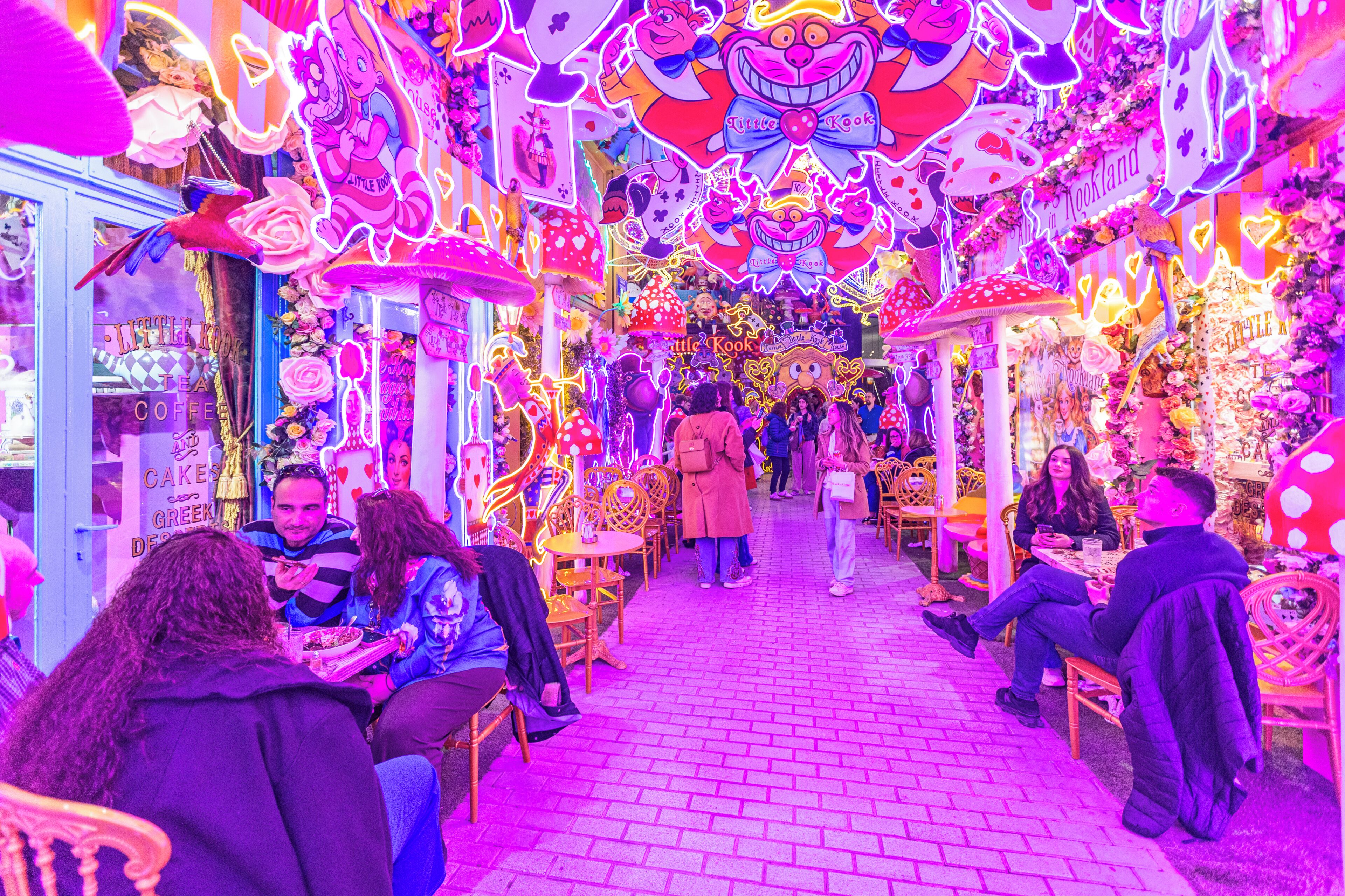 Un ambiente interno luminoso con tavoli e sedie, persone sedute e in movimento.
