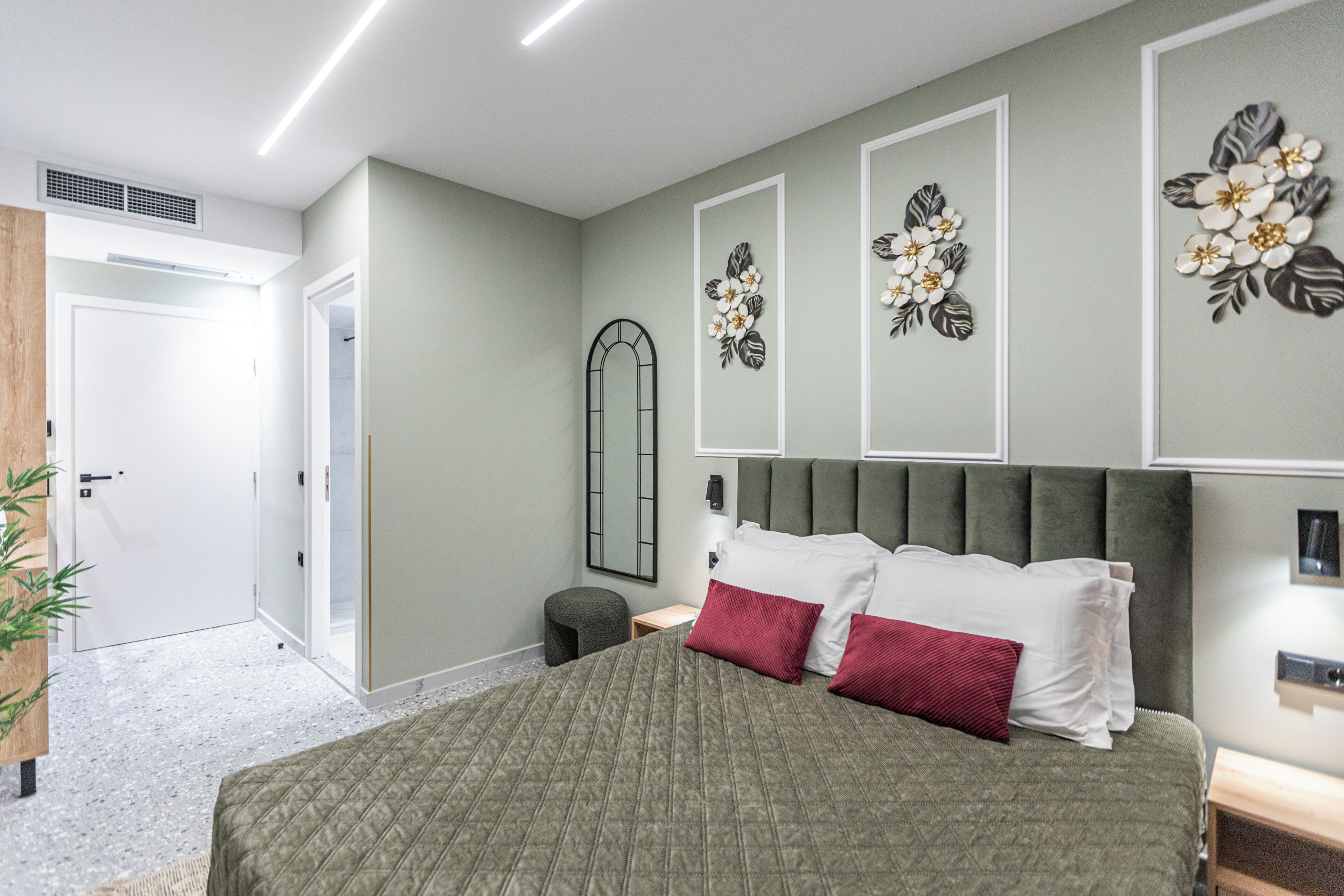 A bedroom with a bed, a nightstand, a mirror, and wall art.