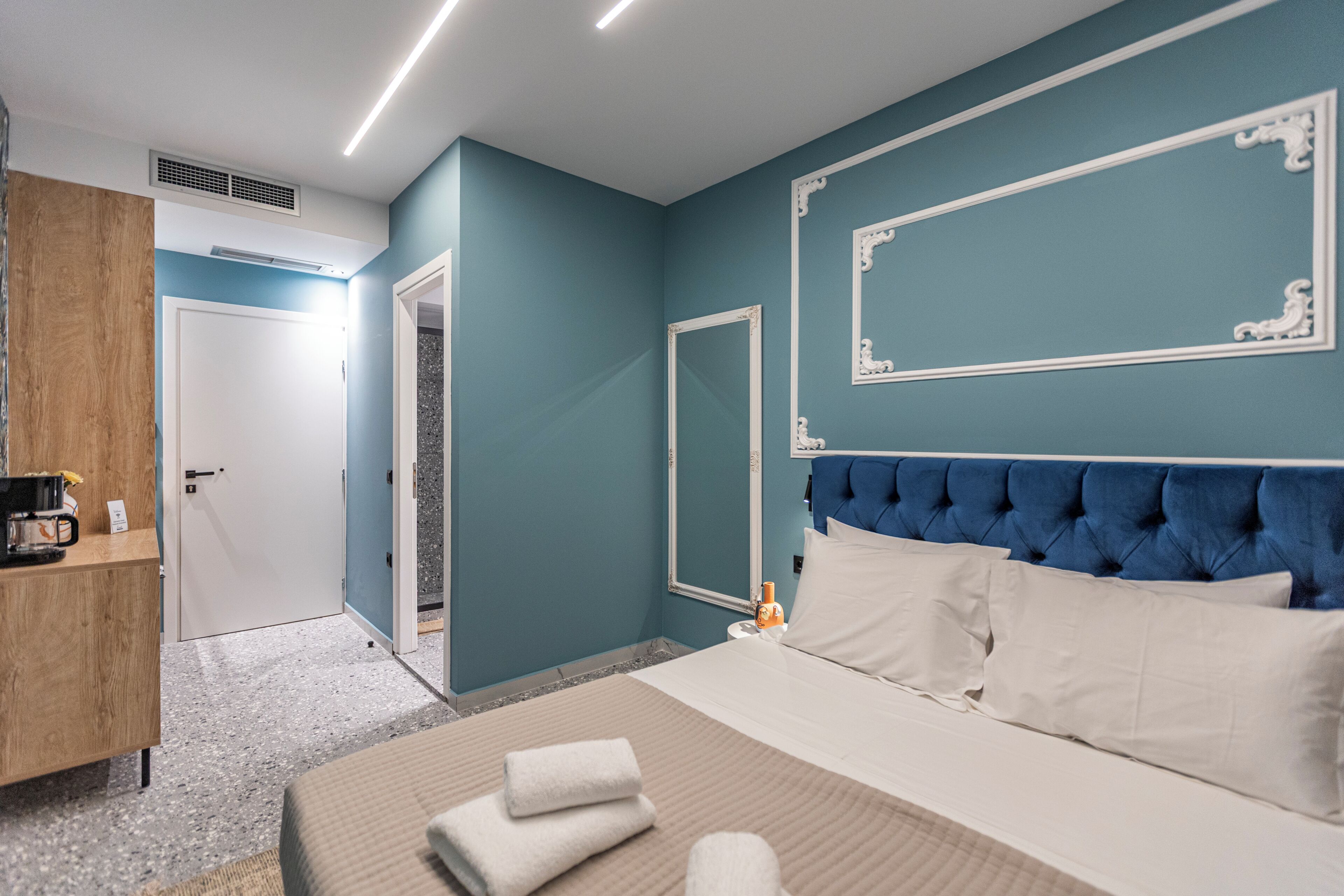 Habitació d'hotel amb un llit, un taulell de fusta, una porta de bany i un mirall gran a la paret.