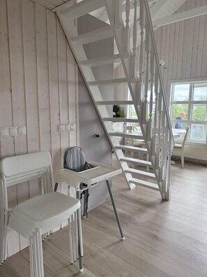 A room with a white staircase, a white chair, and a small table.
