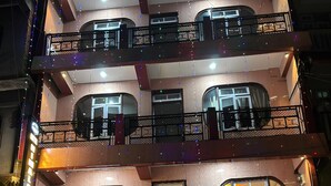 Un edificio a più piani con balconi, un cartello che indica un ristorante e una motocicletta parcheggiata davanti.