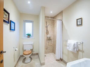 Een badkamer met toilet, douche en bad.