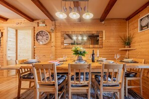 A wooden dining room with a large round table, chairs, a clock, and a mirror above the table. - Rural home in nature with jacuzzi, sauna and entertainment amenities (Mazin)