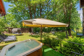 A backyard with a hot tub, lounge chairs, a covered patio, and a playground. - Rural home in nature with jacuzzi, sauna and entertainment amenities (Mazin)