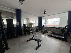 Ein Fitnessraum mit Trainingsgeräten, einer Bank und einem Laufband.