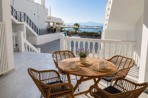 A balcony with wicker chairs and a table, overlooking a pool and a mountainous landscape. - Beachfront Escape in Mikra Mantinia-Messinian Aura (Archontiko)