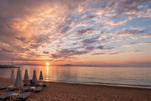 A beach with lounge chairs and umbrellas, a sunset, and calm water. - Beachfront Escape in Mikra Mantinia-Messinian Aura (Archontiko)