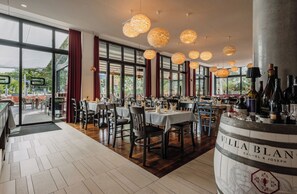 A restaurant interior with tables, chairs, hanging spherical light fixtures, and a wine barrel display. - Grimms Potsdamer Platz (Berlin)
