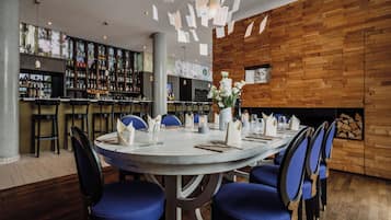 A restaurant with a round table set for dining, bar area with various bottles, and a wooden wall.