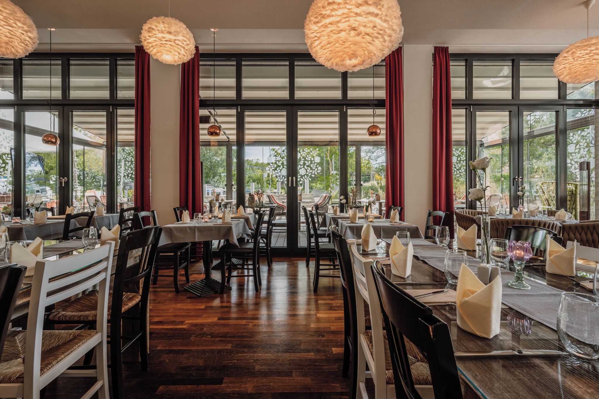 A restaurant with multiple dining tables, chairs, and hanging pendant lights.